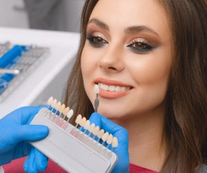 A woman smiling with a set of veneers in front of her.