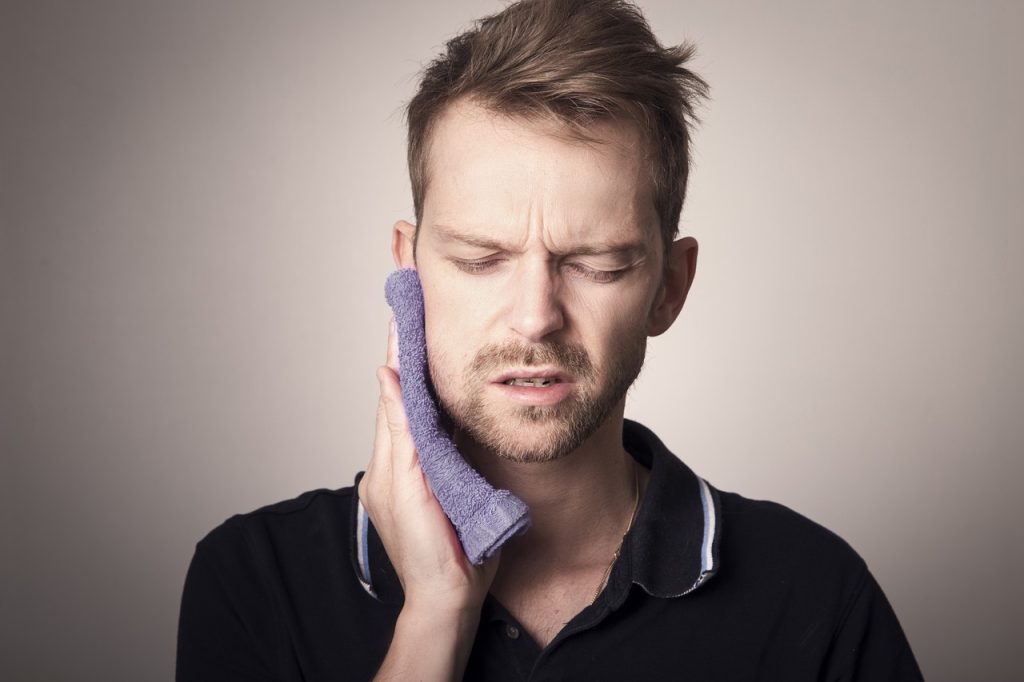 Man holding a cloth against his jaw area showing discomfort