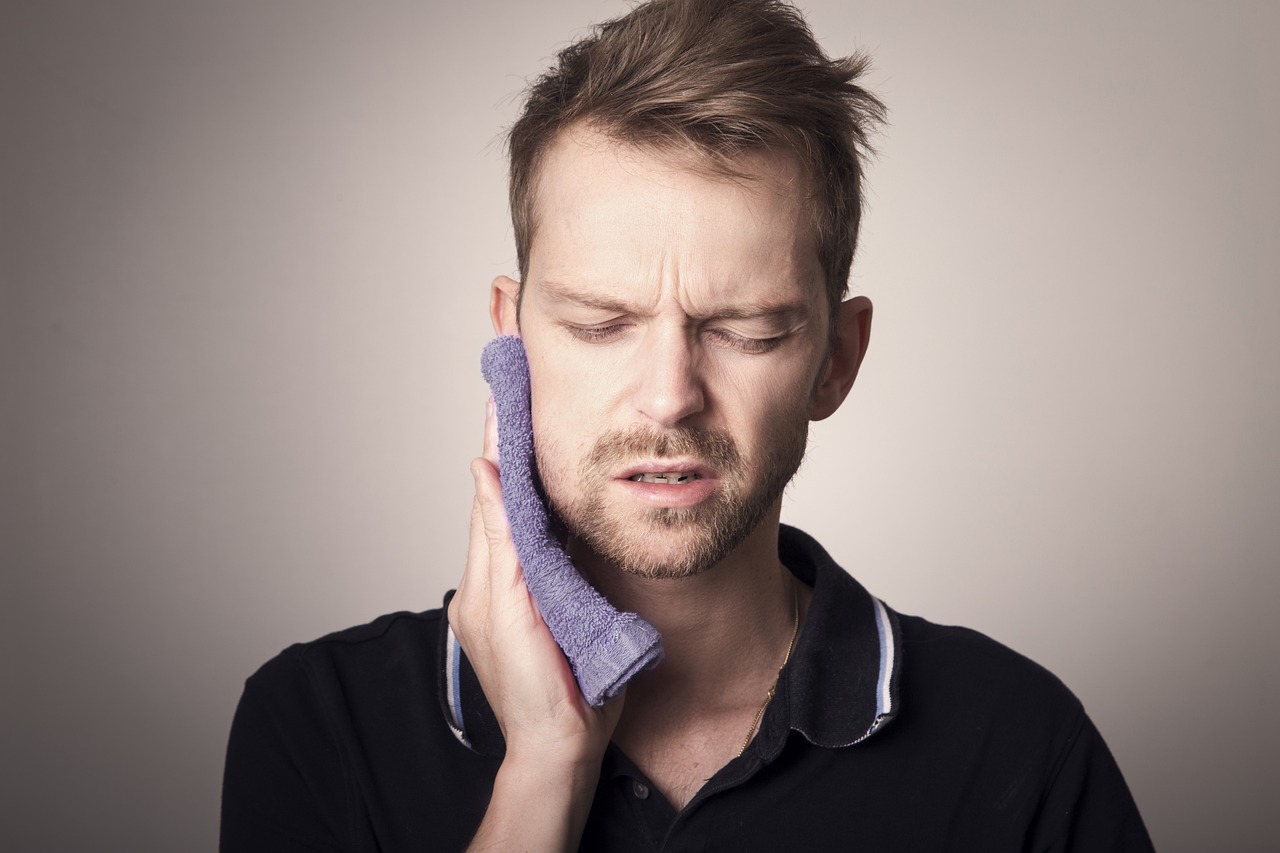 Man holding a cloth against his jaw area showing discomfort