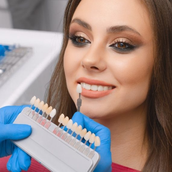 A woman smiling with a set of veneers in front of her.